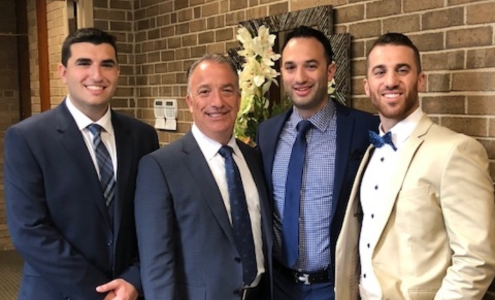 A photo of George Hannoush and his sons Abe, Andre, and Anthony, standing in front of a brick wall.