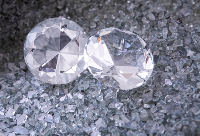 A close-up of two stunning round cut diamonds displayed atop small diamond trimmings.