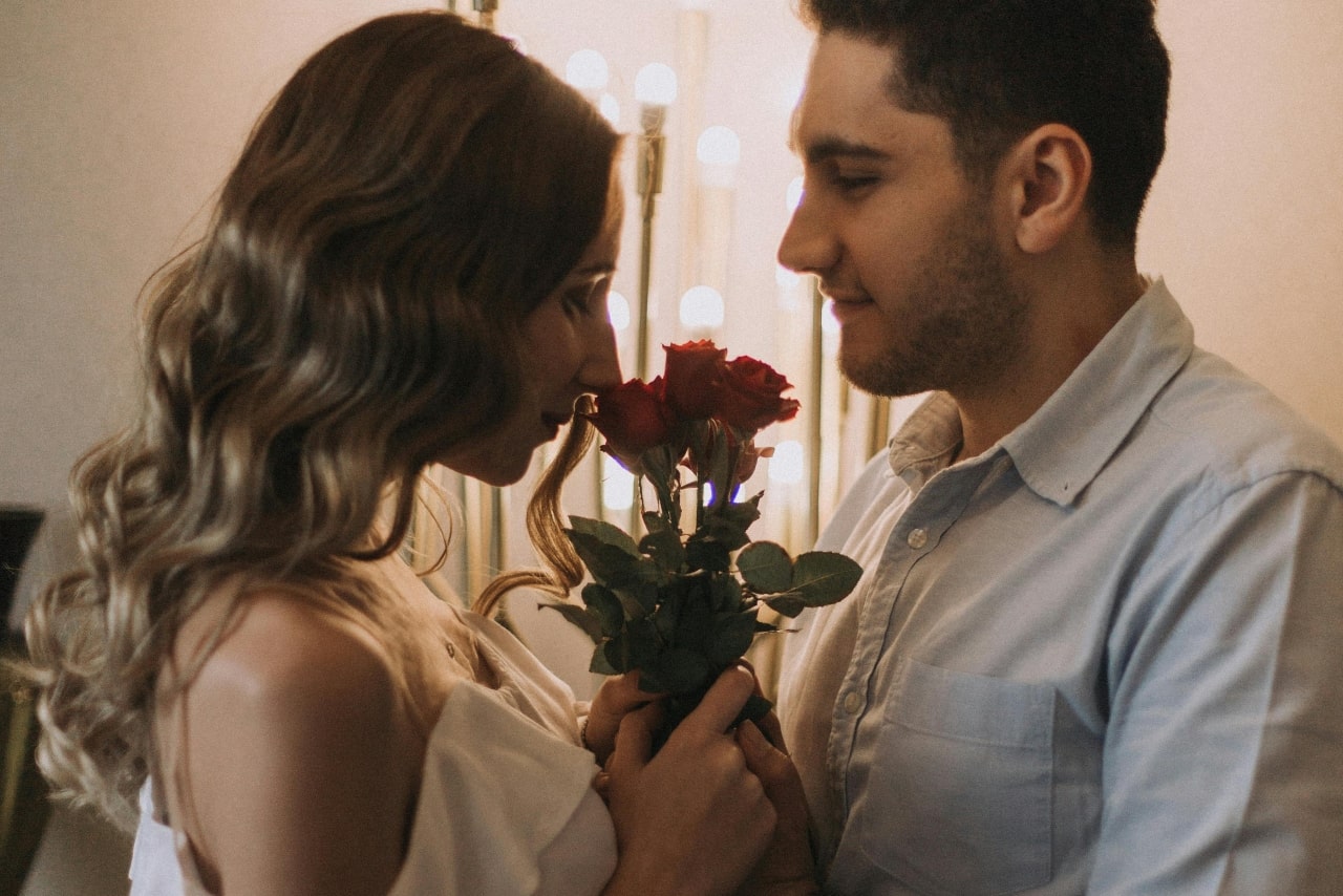 A woman smelling the roses her significant other got her and is holding