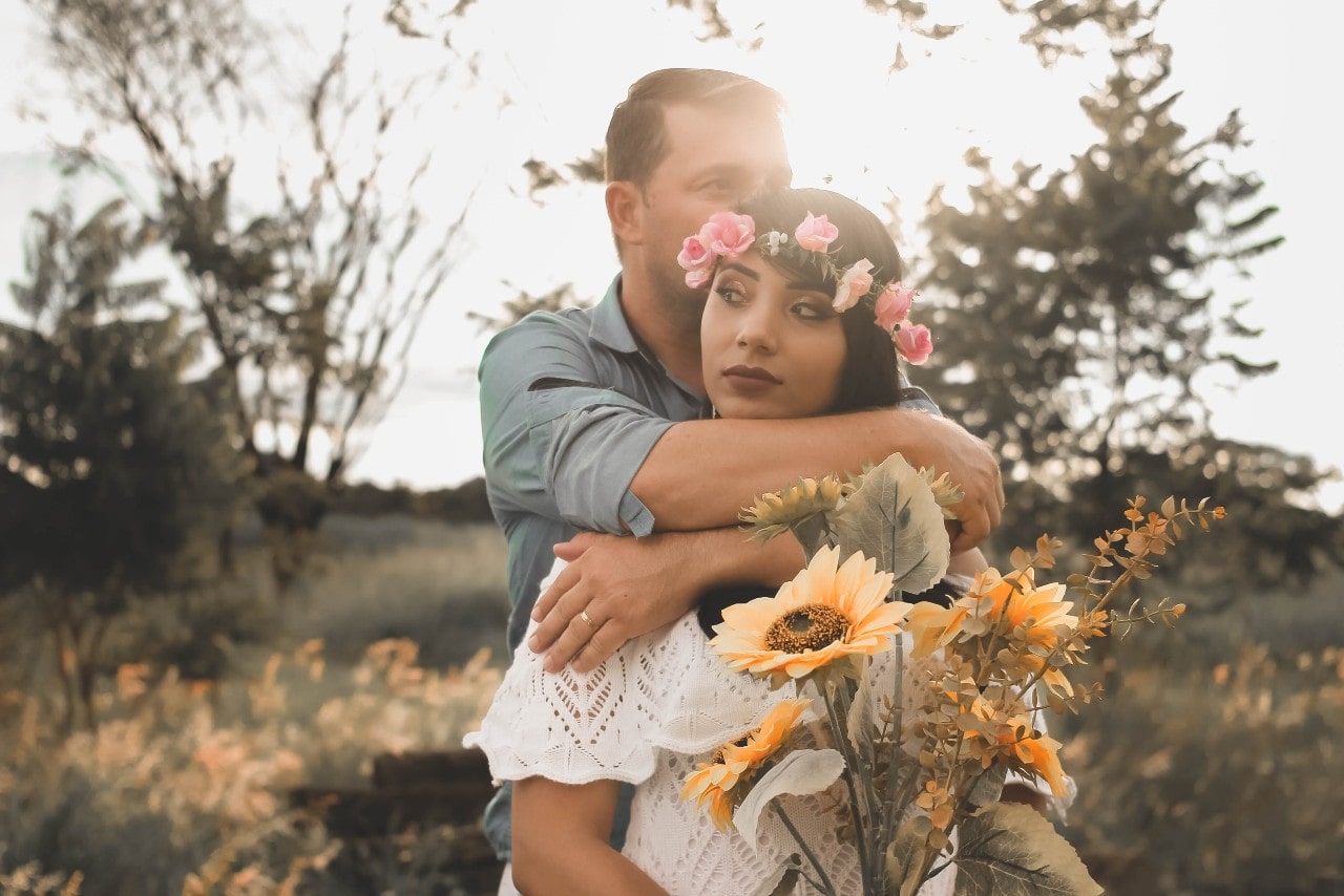 a man and woman embracing outside in the sunlight