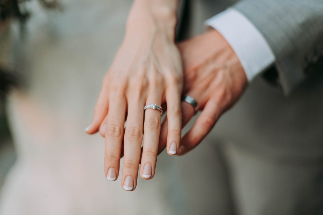 a man and woman’s hands wearing wedding bands