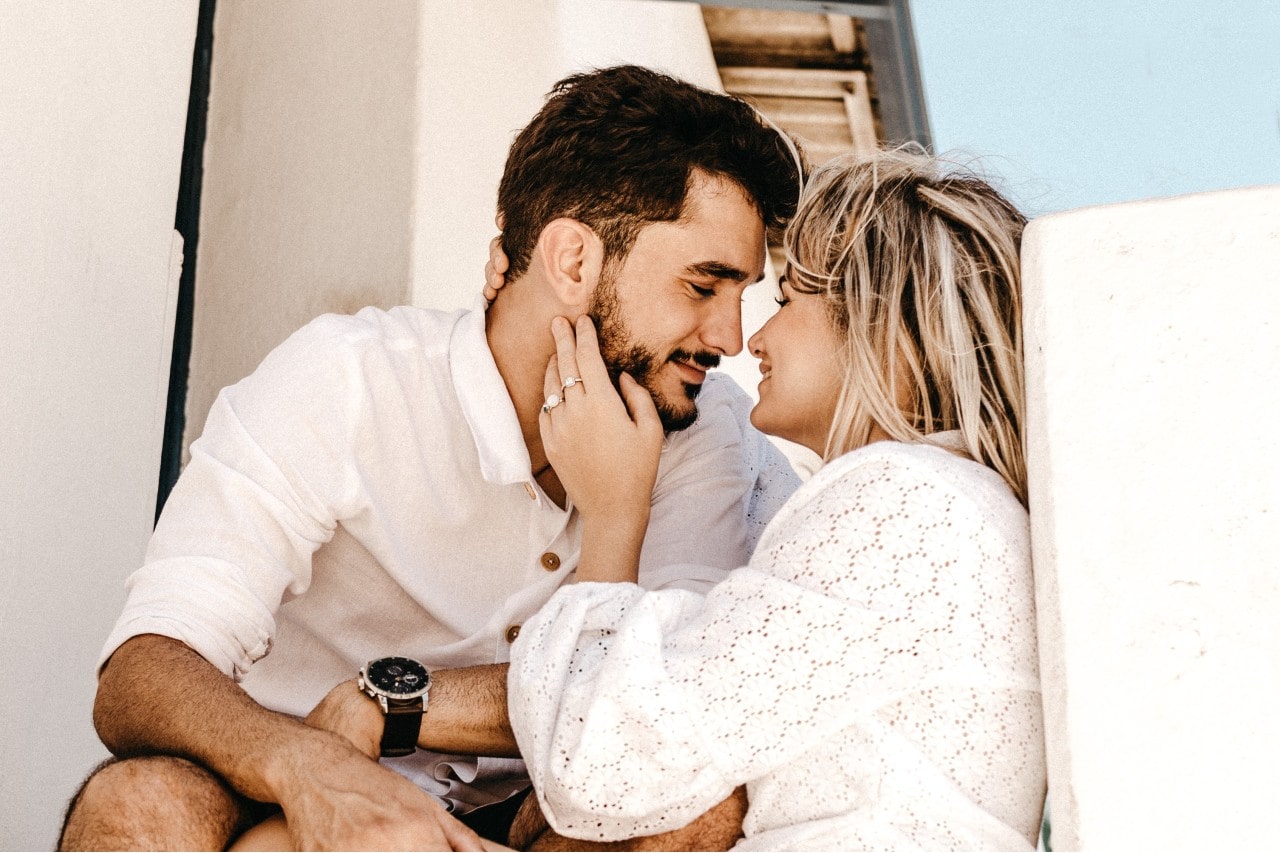 a lady wearing an engagement ring and embracing a man