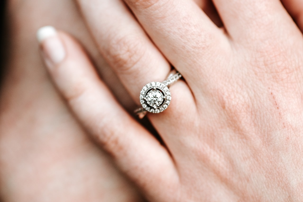 a lady’s hand wearing an engagement ring