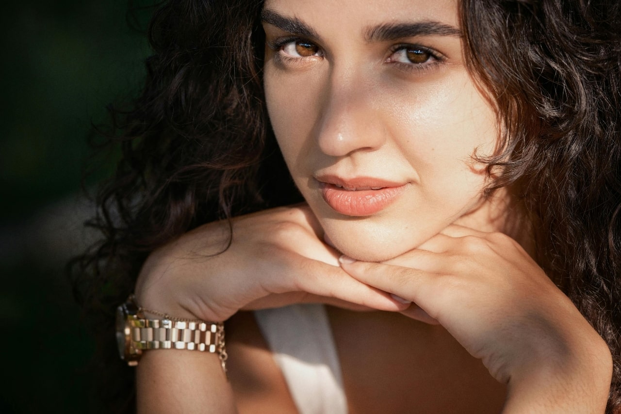 A view of a casually dressed young woman wearing an elegant yellow gold watch.