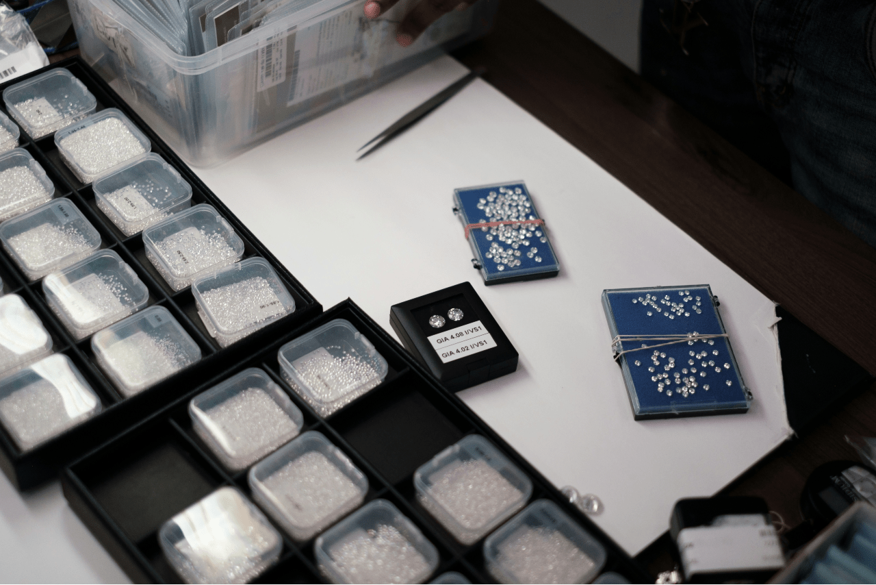 An overhead view of a wide selection of loose diamonds organized into individual plastic containers.