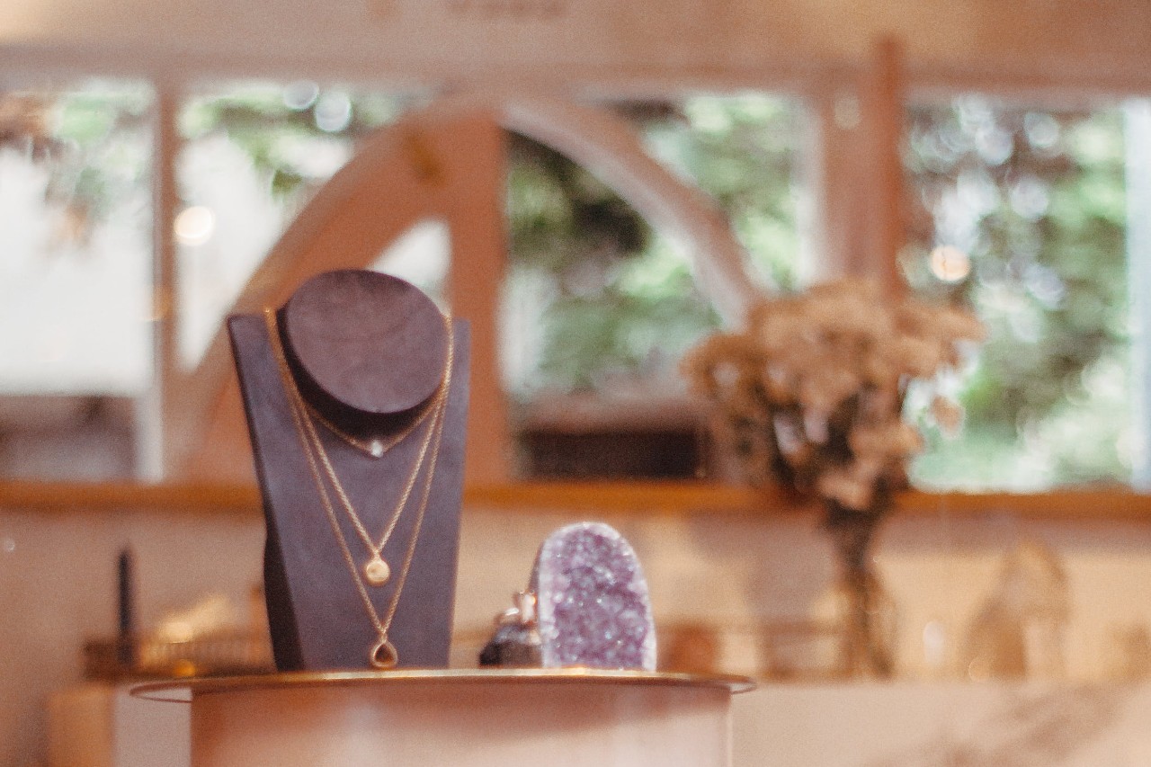 A close-up of a necklace display and geode in a pristine jewelry showroom.
