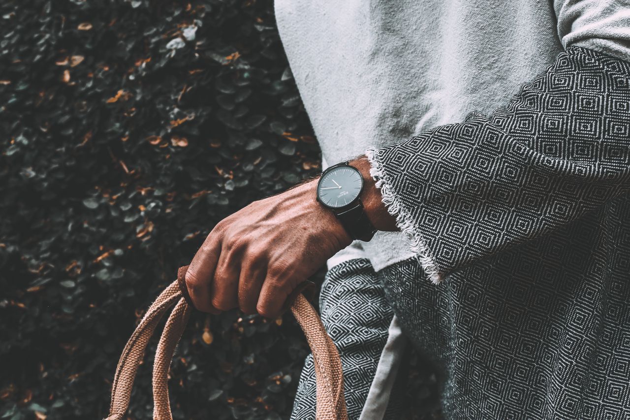 Guy with a black timepiece walks whilst holding a bag