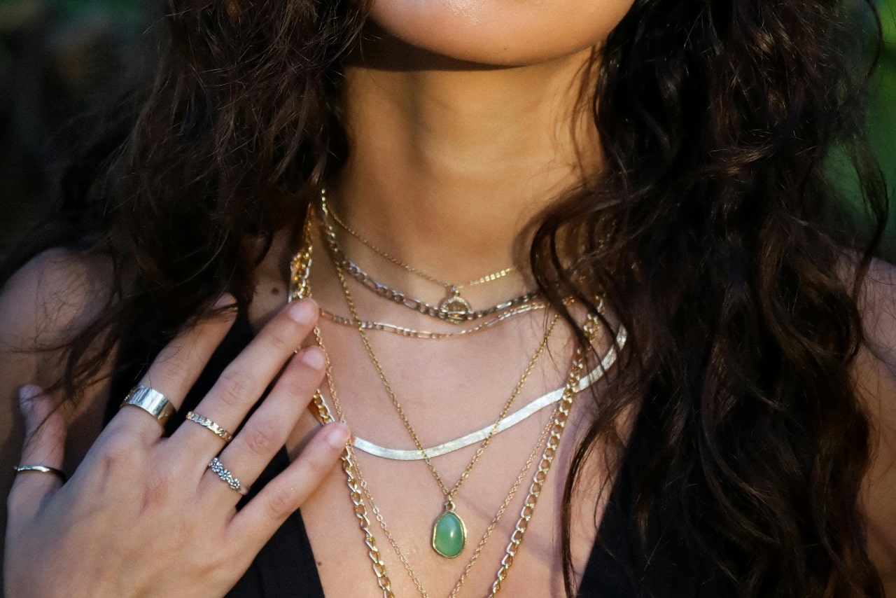 A close-up of a fashionable woman’s decolletage adorned with multiple styles of layered necklaces and elegant fashion rings on her hand. A close-up of a fashionable woman’s decolletage adorned with multiple styles of layered necklaces and elegant fashion rings on her hand.