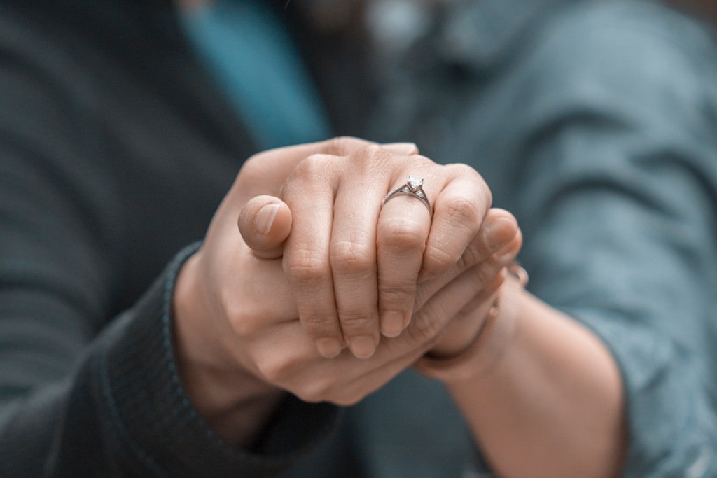 Woman holding hands with pear shape diamond ring