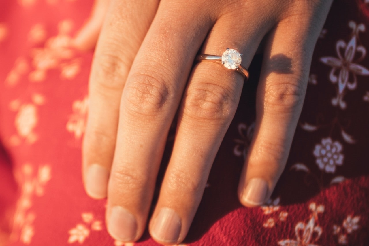 Woman’s hand wearing a round cut diamond engagement ring