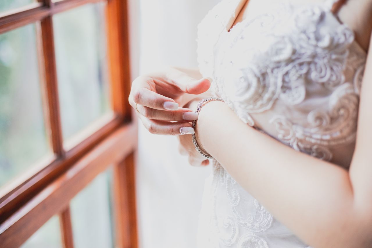 A bride in her wedding dress adjusting a diamond bracelet on her wrist