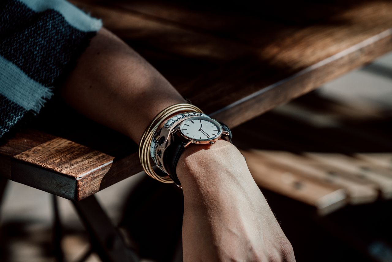 Close up image of a person’s wrist wearing a silver watch and bangle bracelets