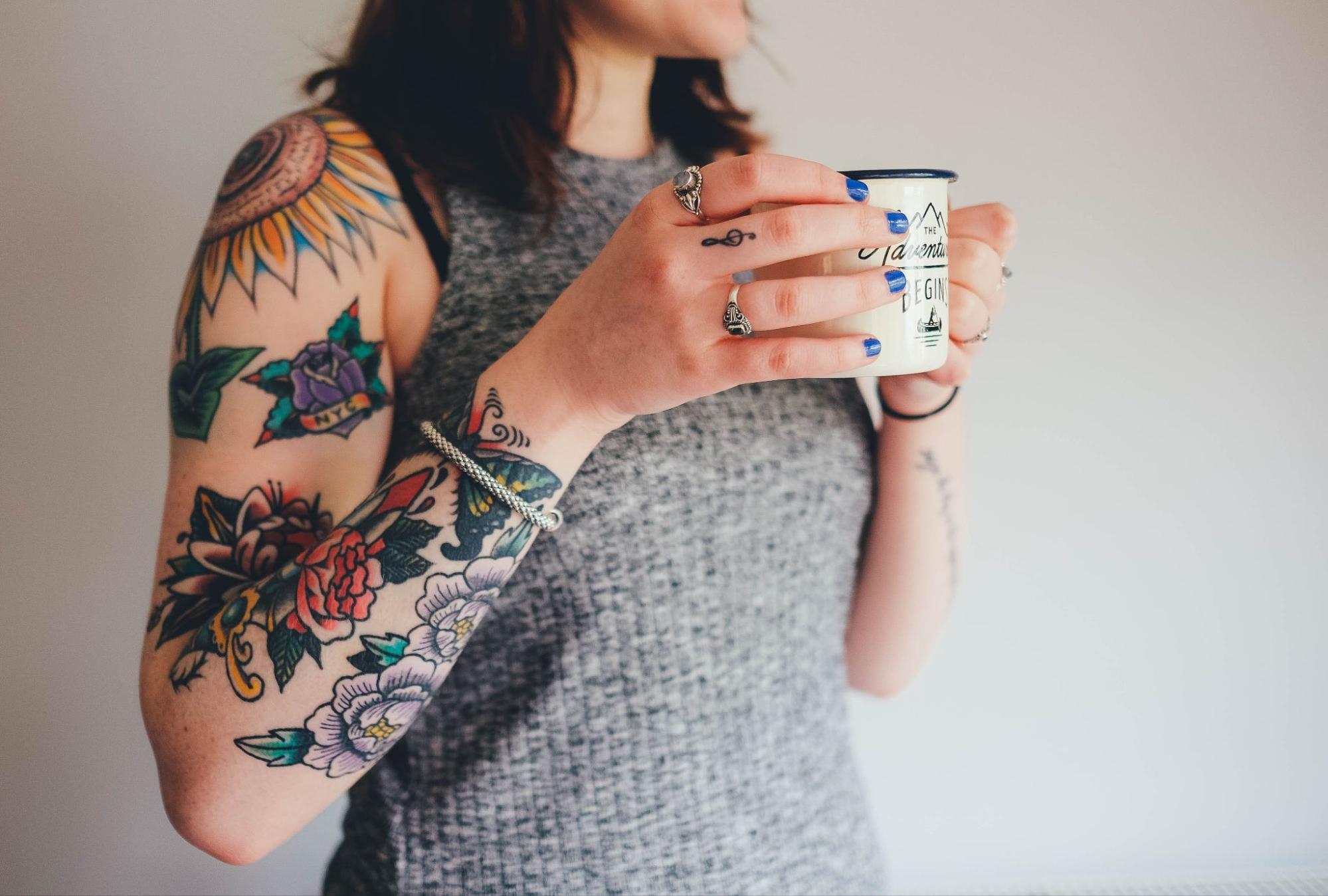 A woman holding a coffee cup and wearing a silver bracelet and rings