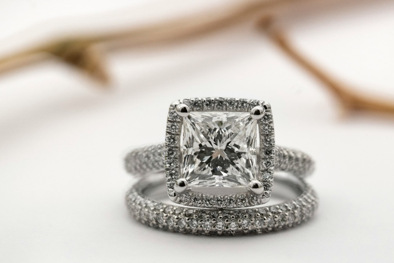 A close-up photo of a cushion cut halo engagement ring and matching wedding band.
