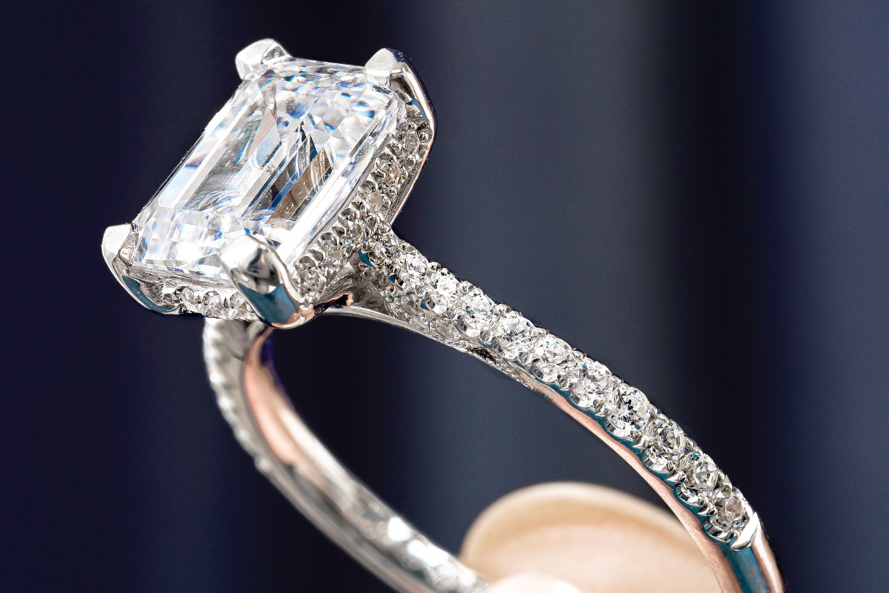 close up image of a white gold engagement ring with an emerald cut center stone