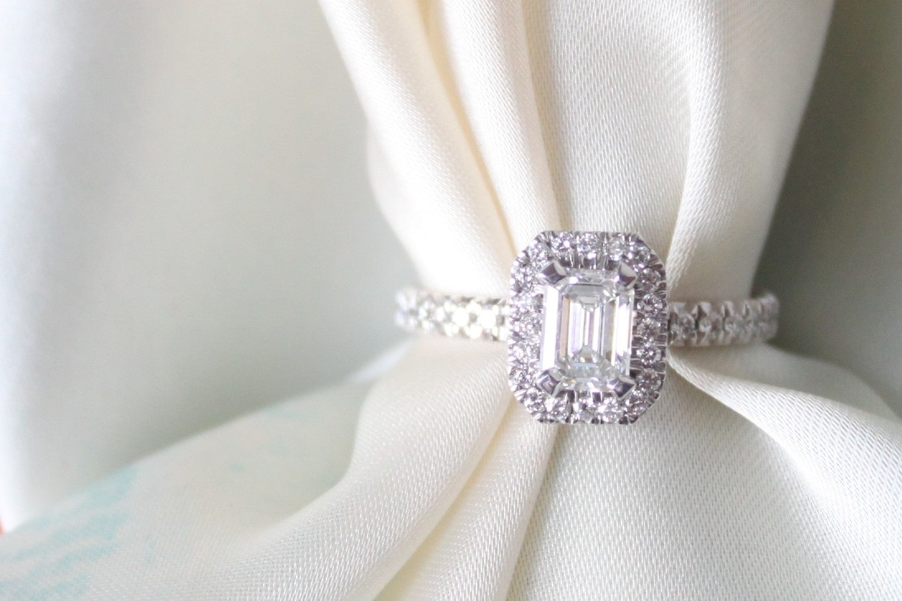 a white gold halo engagement ring on a piece of white fabric
